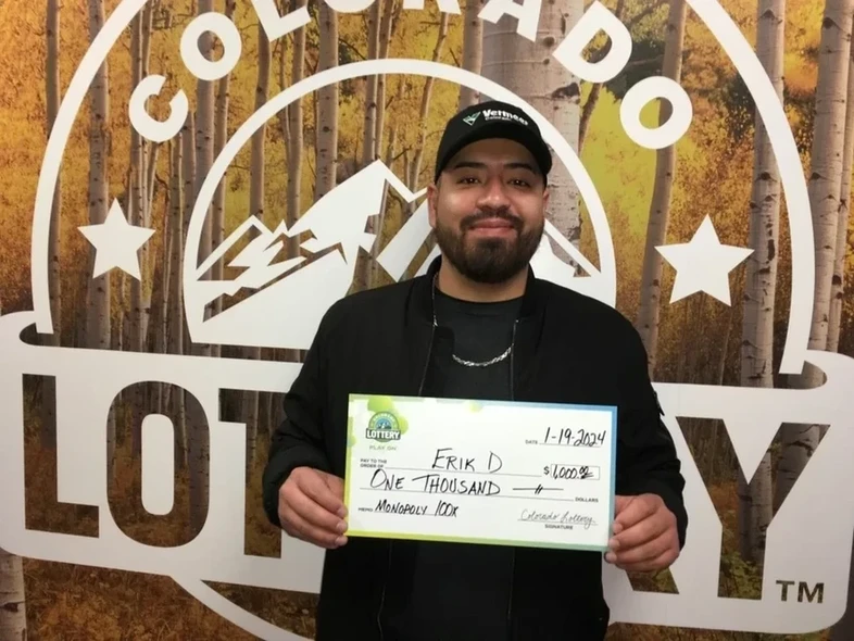Erik D. 手持一张 $1,000的特大支票，背景是科罗拉多彩票