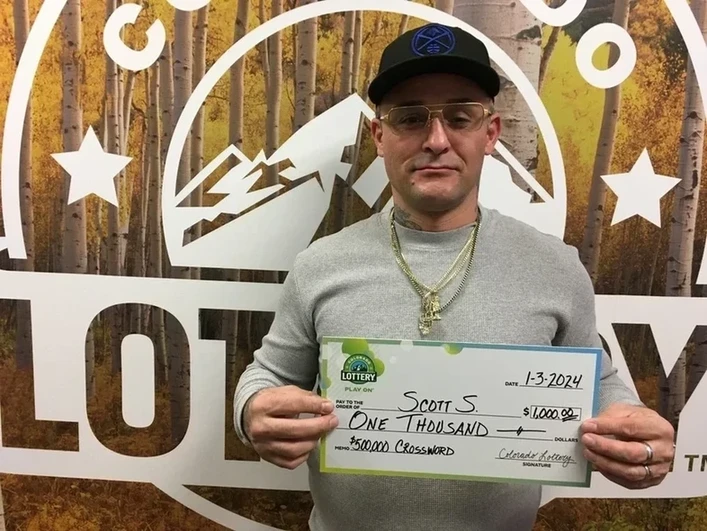 Scott S. 手持一张价值 $1,000的大支票，背景为科罗拉多州彩票