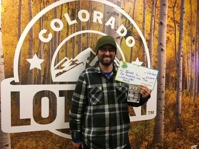 Shane L. 手持一支价值 $10,000的巨型支票，背景是科罗拉多州彩票